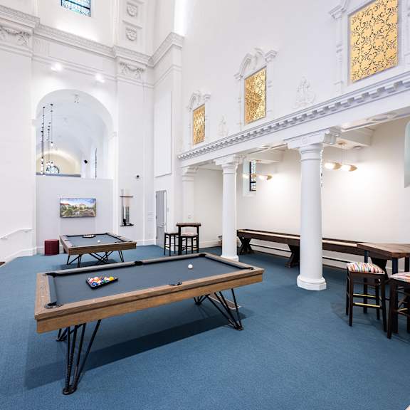 A billiard table is in the middle of a room with white walls and a white ceiling.