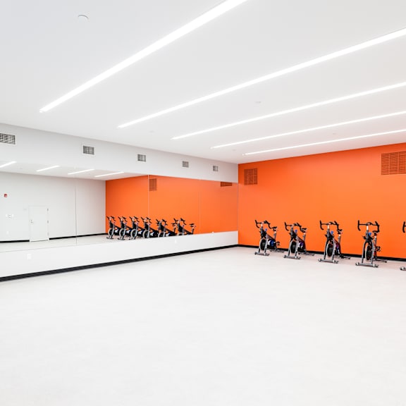 A room with orange walls and exercise bikes.