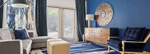A blue and white room with a couch, chair, ottoman, and a lamp.