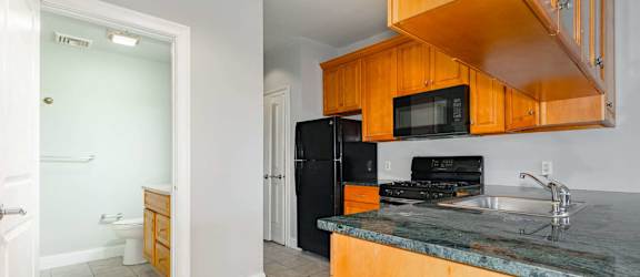 A modern kitchen with wooden shelves and black countertops.