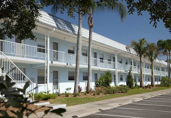 A row of white buildings with balconies and palm trees in front. at Imperial Gardens Apartments, Clearwater, FL, 33764