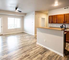 A room with a kitchen area and a ceiling fan at Meadowlark Place Apartments, Grimes, IA