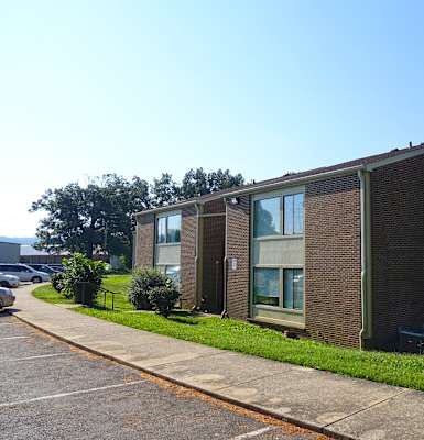 a brick building with green grass and a blue sky in the background