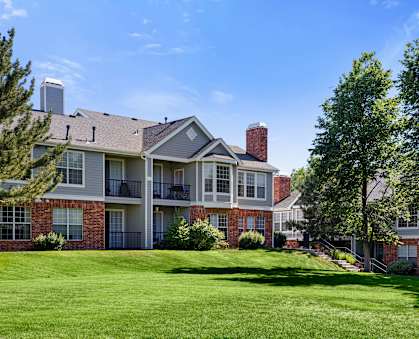 A large, well-maintained apartment complex with a green lawn in front.