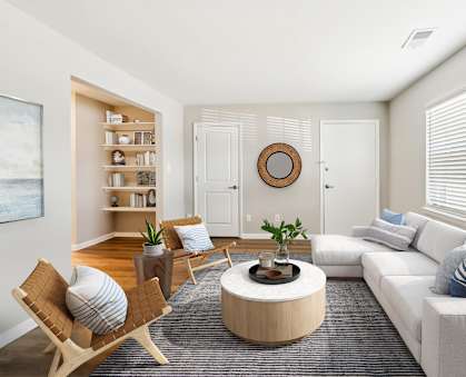 A living room with a white couch, a wooden coffee table, and a painting on the wall. at Rivers Landing Apartments, Hampton, Virginia