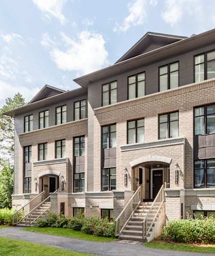 A large, modern house with a flat roof and a staircase leading to the entrance.