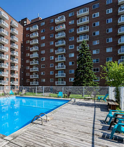 A large swimming pool in front of a red brick apartment building.