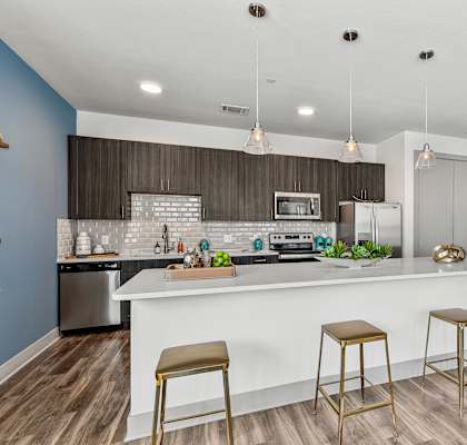 A kitchen with a white counter and bar stools.