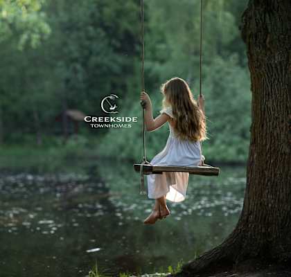A girl is sitting on a swing in a forest.