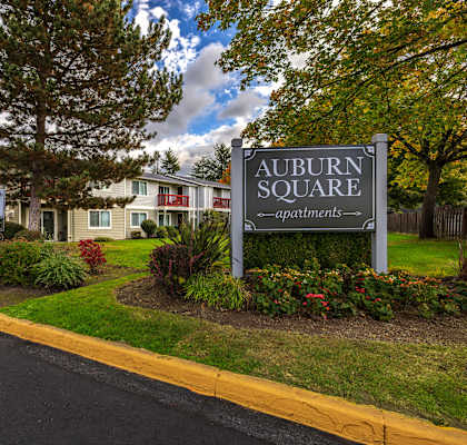 A sign for Auburn Square apartments is in front of a building.
