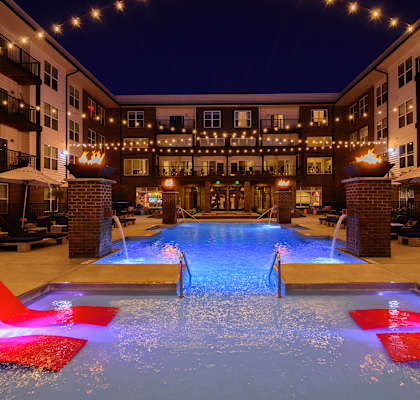 A pool with red chairs and lights around it.