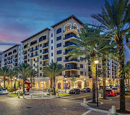 A large hotel with a parking lot in front of it.