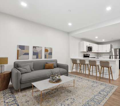 A modern living room with a grey couch, a coffee table at Roosevelt Commons Apartments, Philadelphia