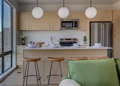 A kitchen with a refrigerator, stove, and bar stools.