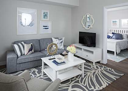 a living room with a gray couch and a white coffee table and a television