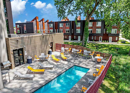 A pool surrounded by chairs and tables in a sunny backyard.at City Square Lofts, Iowa, 50309
