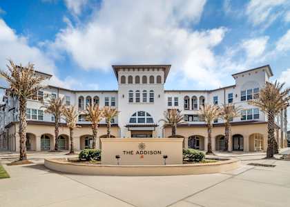 The front of a white building with a sign that says
