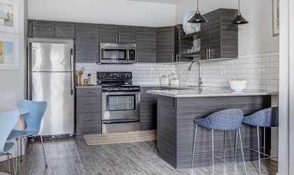 a kitchen with stainless steel appliances and a counter with blue chairs