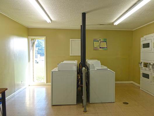a laundry room with yellow walls and white washers and dryers