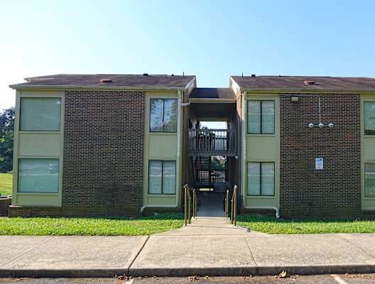 an image of a two story brick apartment building with green walls and a brown roof