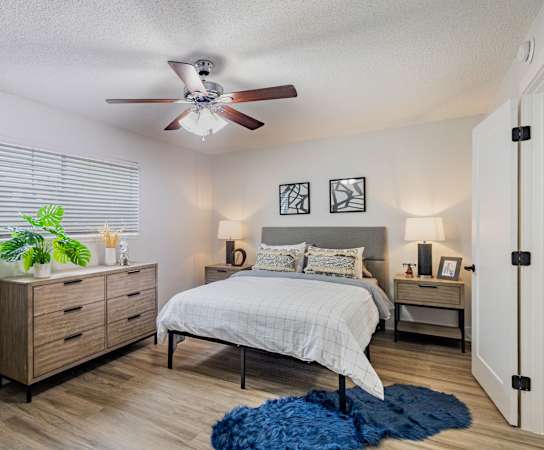A bedroom with a bed, dresser, and ceiling fan.
