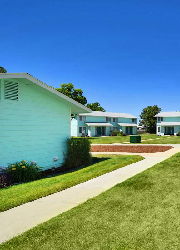 a walkway between two buildings with grass and a sidewalk