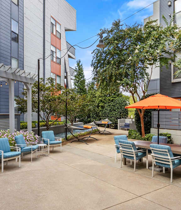 A patio with chairs and tables is surrounded by buildings.