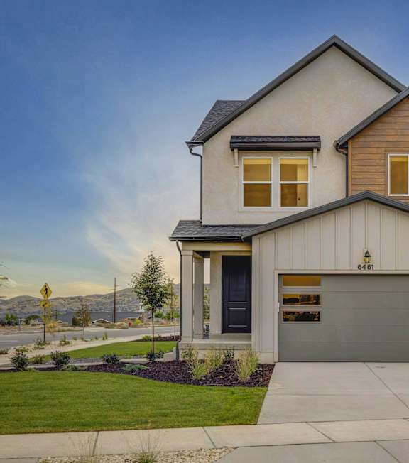 An exterior view of a townhouse with a lawn and an attached garage at Mt. Rainier Herriman townhomes in Utah.