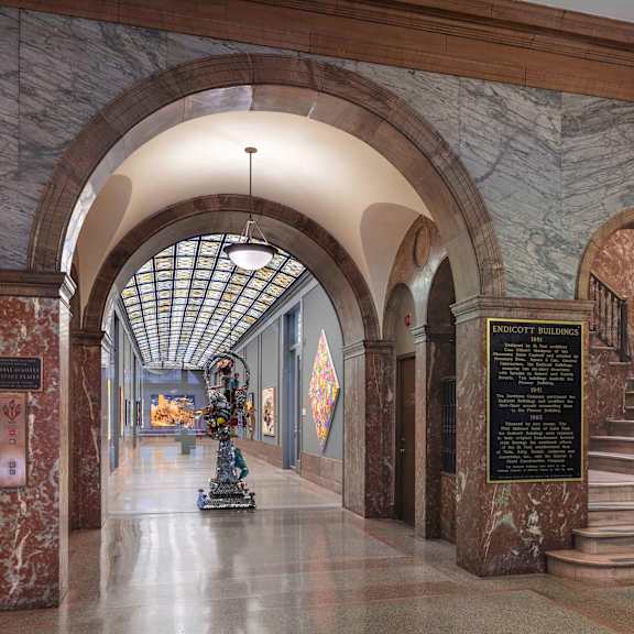 A long hallway with a statue in the middle and a plaque on the wall.