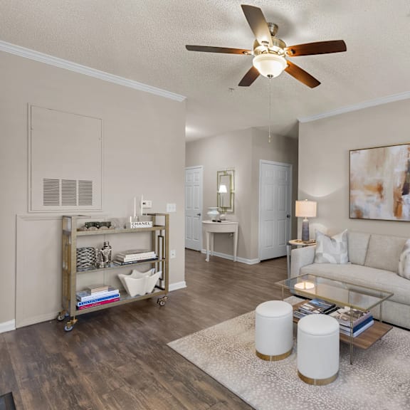 A living room with a white ceiling fan and a painting on the wall.