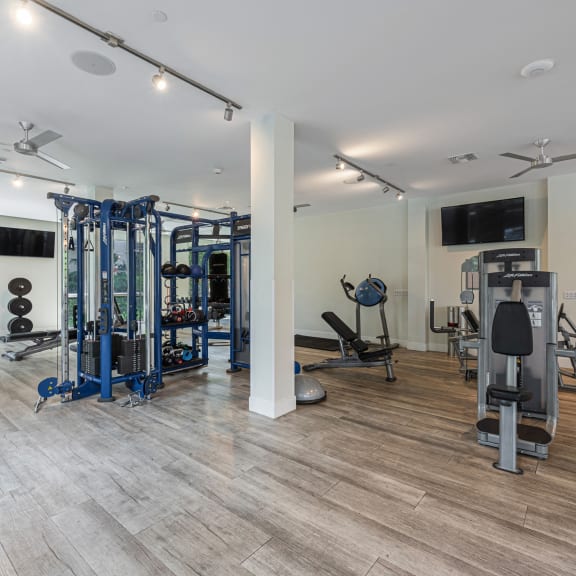 a gym with weights and cardio equipment and a tv