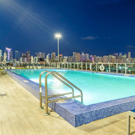 the pool on the roof of a building with a city in the background