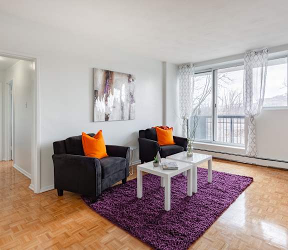 A living room with a black couch, a white coffee table, and a purple rug.