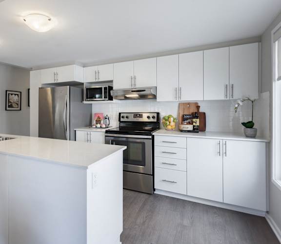 A modern kitchen with white cabinets and stainless steel appliances.