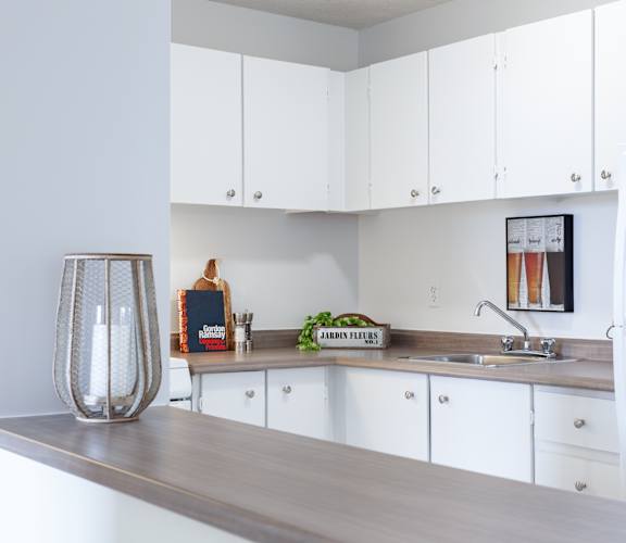 A kitchen with white cabinets and a wooden counter.