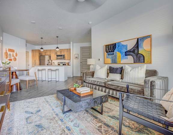 a living room with a couch coffee table and a kitchen in the background