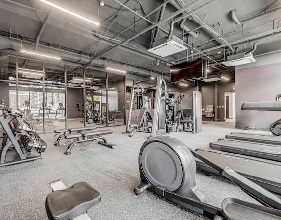 a gym with weights and cardio equipment at the district at highland village apartments