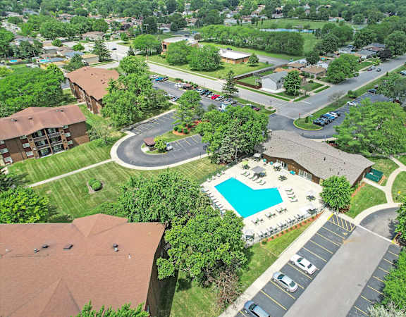 A bird's eye view of a residential area with a swimming pool and a roundabout.