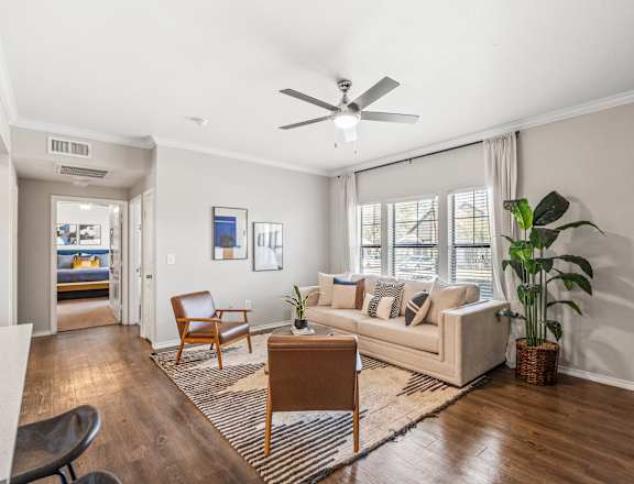 A living room with a couch, chair, and potted plant.