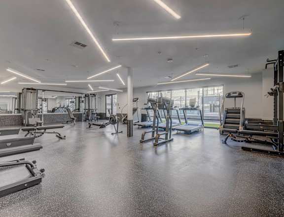 a gym with weights and cardio equipment in a building with windows