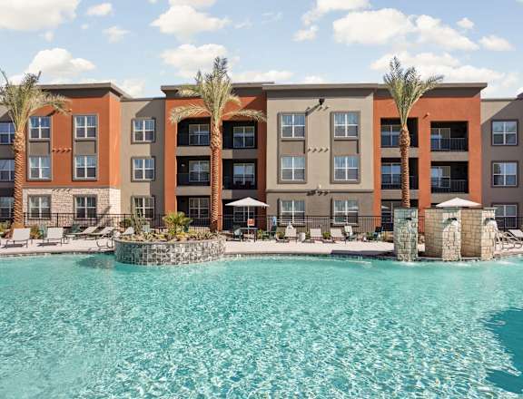 A large swimming pool in front of a multi-story apartment building.