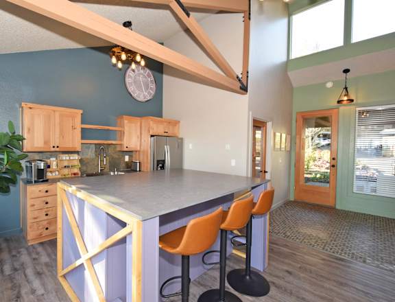 A kitchen with a purple island and orange chairs.