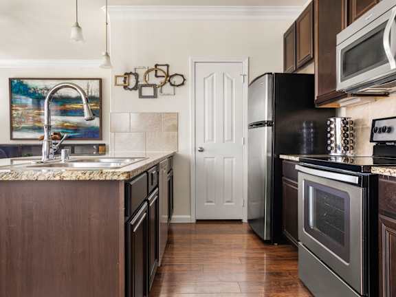 A kitchen with a black refrigerator and stove top oven.