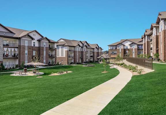 A row of apartment buildings with a green lawn in front.