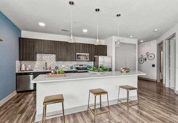 A kitchen with a white counter and bar stools.