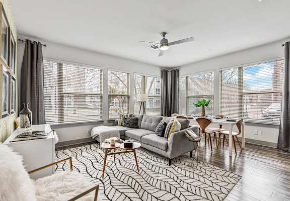 A living room with a grey couch, a coffee table, and a ceiling fan.