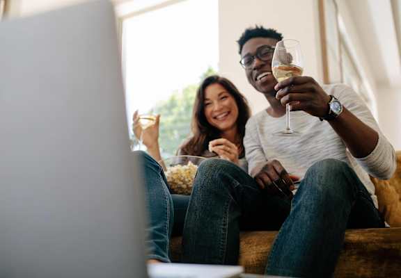 a man and woman sitting on a couch with a glass of wine