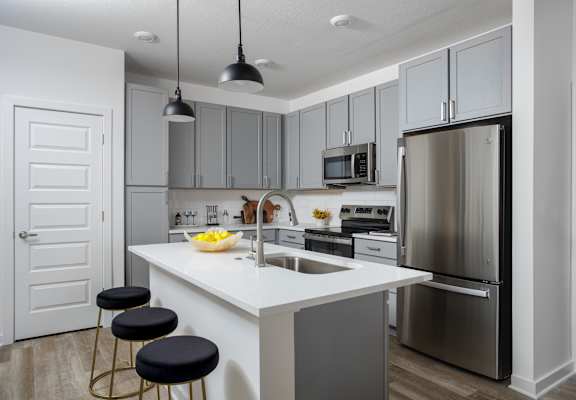 A modern kitchen with a white island and stainless steel appliances.