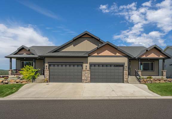 A modern house with a grey garage door and a stone wall.