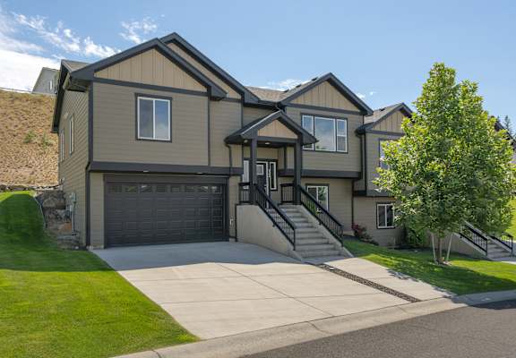 A house with a grey garage door and a black front door.